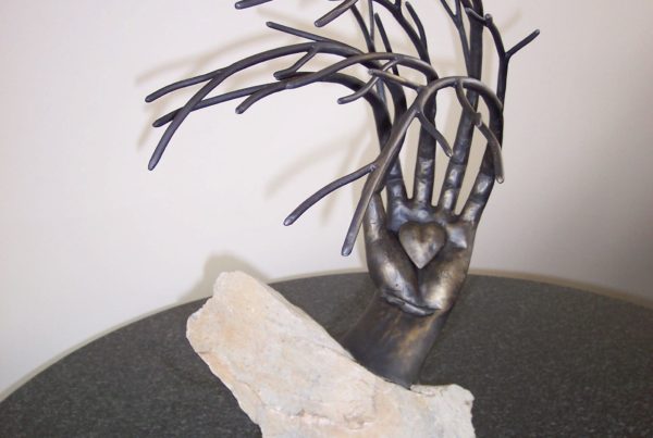 Reka kuta z sercem w kamieniu. Palce w formie galezi drzewa